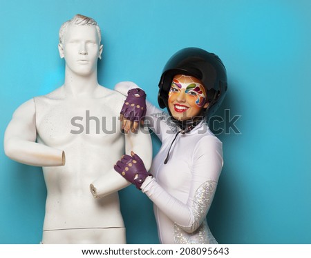 Portrait of a beautiful young model with bright creative make up with helmet and male dummy