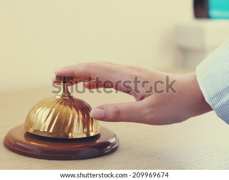 Hand of a woman using a hotel bell in retro style