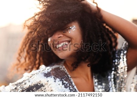 Portrait of overjoyed glamour african american woman with glitter on face in silver sequin dress enjoying outdoor party or event, mixed race female in festive wear with eyes closed feeling happy Stock foto © 