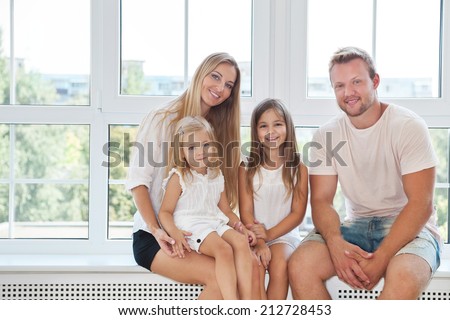 Happy toung family with kids near the window at home