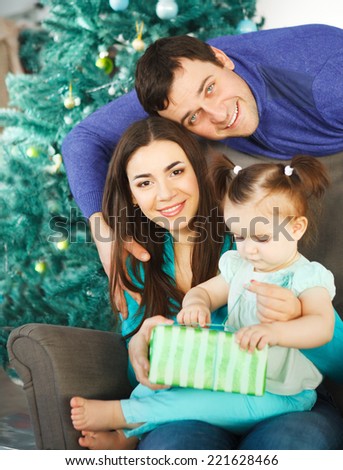 Happy family with Christmas present near the Christmas tree