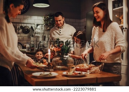 Family preparing traditional festive Christmas Eve dinner together in cozy homely atmosphere, two daughters helping parents to set New Years table, cooking in kitchen decorated for winter holidays Сток-фото © 