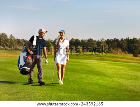 Young sportive couple playing golf on a golf course walking to the next hole