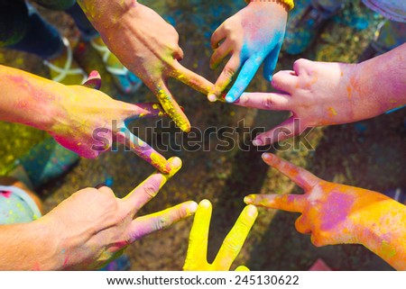 Friends putting their hands together in a sign of unity and teamwork. Holi colors festival. Friendship concept