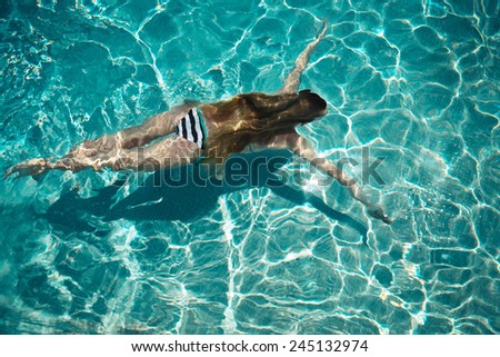 Woman swimming on a blue water pool. Summertime