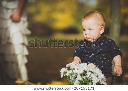 Beautiful baby crawling or sitting in fallen leaves. playing with flowers - fall scene