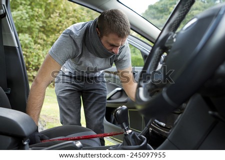 Thief wearing black clothes and leather coat stealing a car