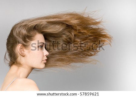 The beautiful long-haired girl on a grey background