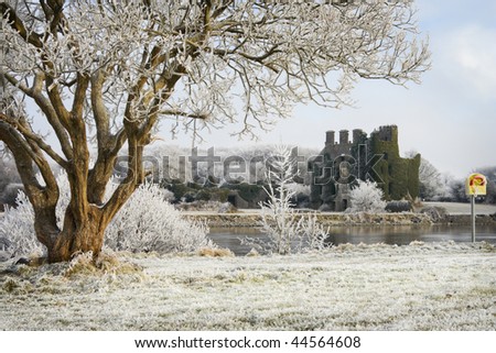 Irish castle ruins and trees covered by frost on cold winter day