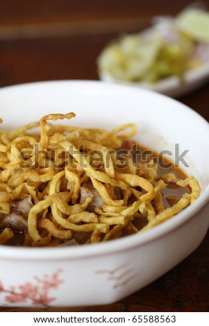 thai food Khao soy a famous northern noodle dish in beef curry with wood background