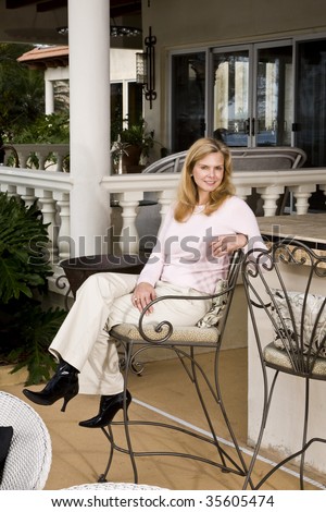 Portrait of smiling mature woman sitting on wrought iron barstool on patio