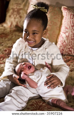 Grinning four year old girl sitting next to newborn sibling
