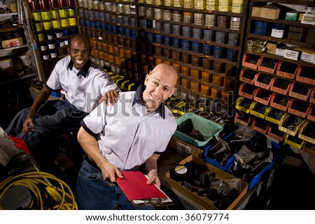 Male coworkers working in front of colored inks in print shop