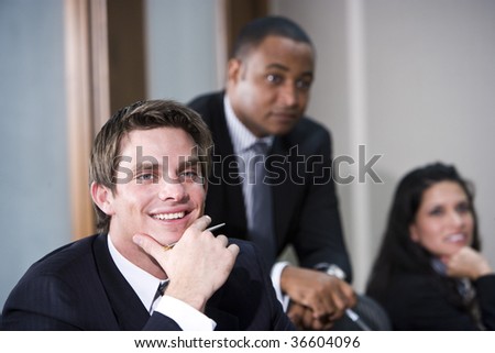 Confident young businessman with African American and Hispanic colleagues in background