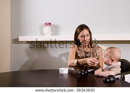 Mother feeding six month old baby sitting in high chair