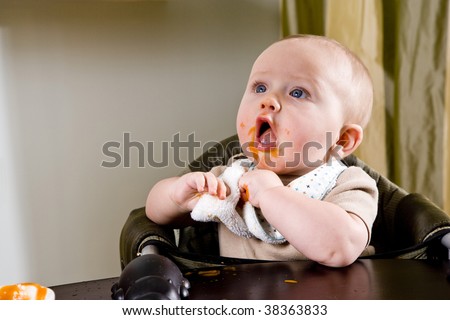Cute hungry six month old baby eating solid food