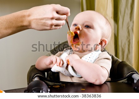 Hungry six month old baby eating solid food from a spoon