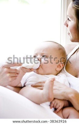 Close up of mother daydreaming while feeding bottle to baby
