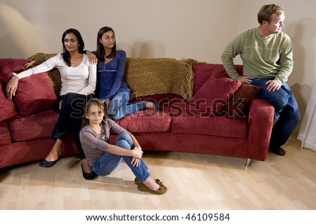 Family argument - girls on one side of sofa with father sitting apart