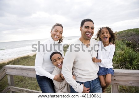 Happy African-American family with two children laughing at beach