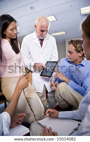 Professor wearing lab coat having discussion with college students