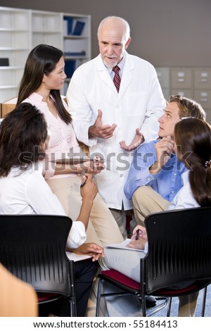 Professor wearing lab coat having discussion with college students