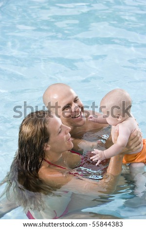 Parents with 6 month old baby playing in swimming pool