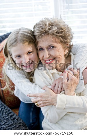 Portrait of happy young girl hugging grandmother at home