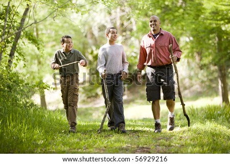 Father and two sons hiking on trail in woods and talking