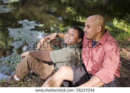 Portrait Hispanic father and son outdoors by pond having conversation