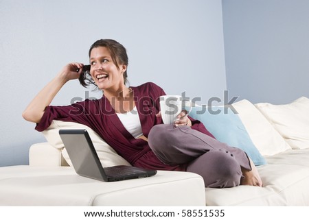 Modern woman relaxed on couch with mobile phone and laptop computer