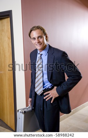 Businessman in suit walking down office hallway with briefcase