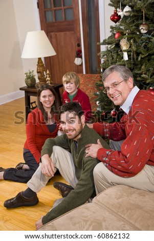 Family holiday portrait - grandfather with family sitting by Christmas tree