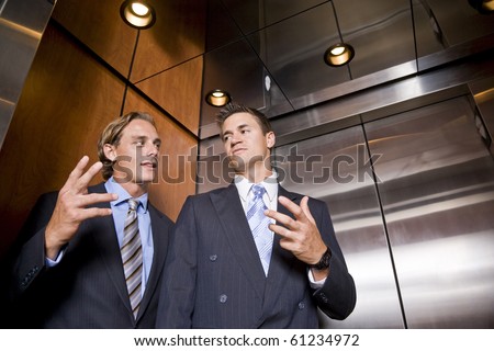 Businessmen riding in elevator conversing
