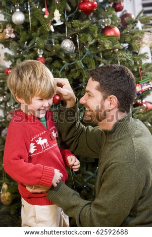 Father and 4 year old son playing in front of Christmas tree