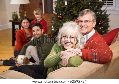 Senior couple with family by Christmas tree - three generations