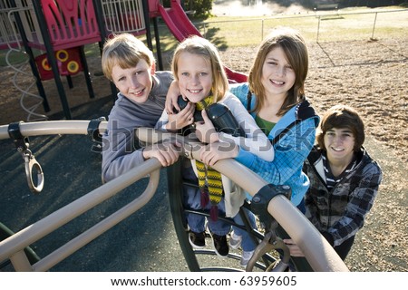 Group of children (10 to 15 years) standing together on playground equipment