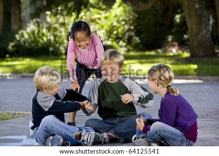 Children playing, teasing and laughing on driveway, ages 7 to 9.