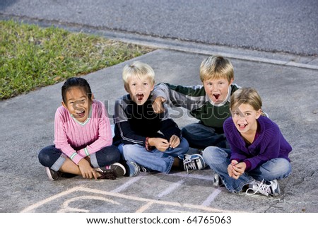 Four kids ages 7 to 9 sitting together on drive laughing and shouting