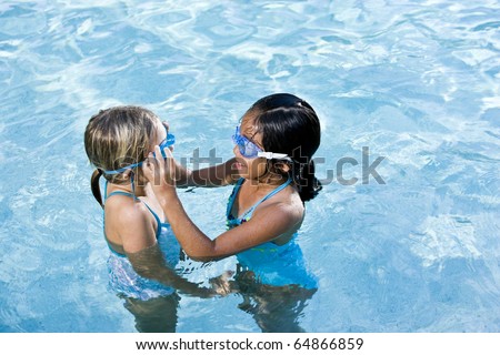Girls, 7 years, adjusting swim goggles in swimming pool