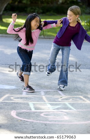 Multiracial friends having fun playing hopscotch on driveway