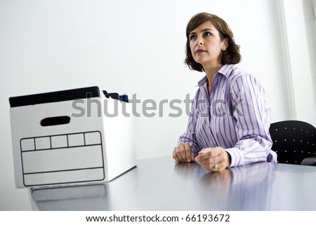 Female office worker, 40s, sitting at office table with cardboard file storage box