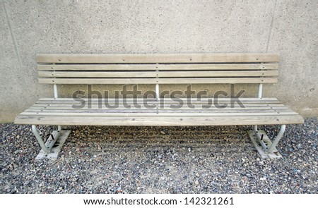 Brown old wood bench in the street next a wall