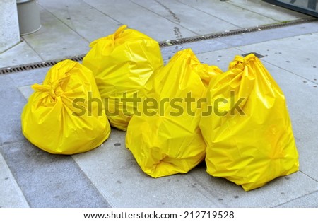 Four yellow garbage bags on the street
