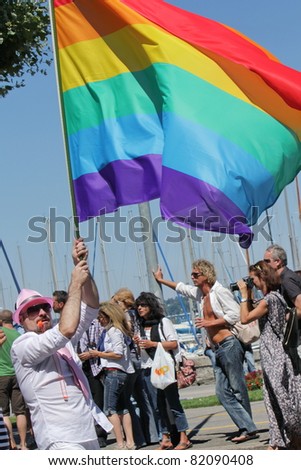 GENEVA, SWITZERLAND - JULY 2 : An unidentified man holding a big rainbow flag while taking part in Gay Pride Parade 2011 to support gay rights, on July 2, 2011 in Geneva, Switzerland.