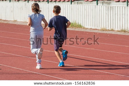 girl and boy jogging on tartan track