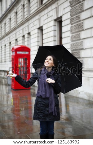 Beautiful woman in London in a rainy day, holding an umbrella
