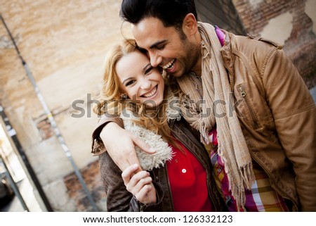 Young couple in a candid shot. They are walking in the street.