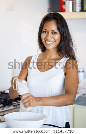 Woman making almond milk at home, squeezing the cheese cloth to filter it. A vegan healthy option.