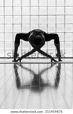Young woman practicing in a yoga studio. Artistic shot showing reflection and lines.